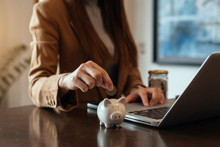 woman hand putting coin into piggy bank