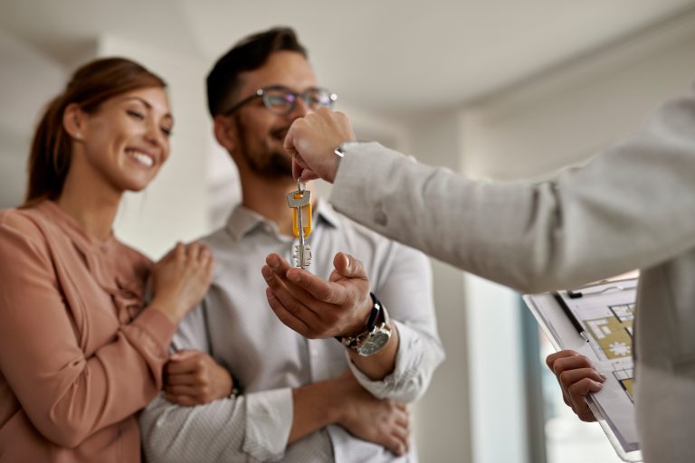 Close-up of real estate agent giving new house keys to a couple